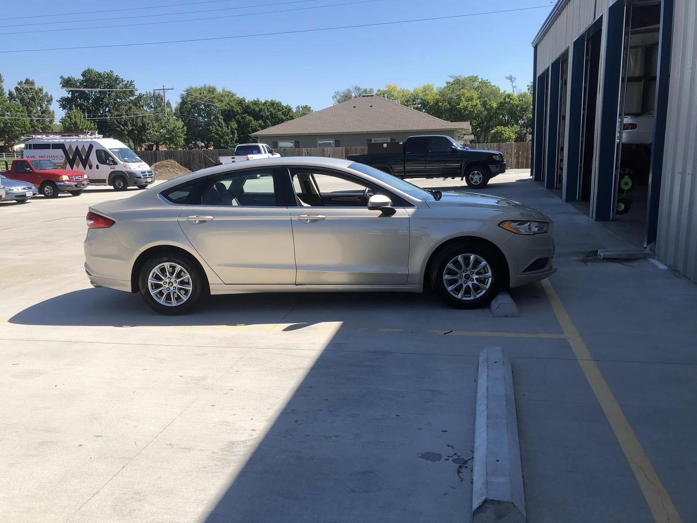 The shop's bay doors and navy trim seen across the parking lot